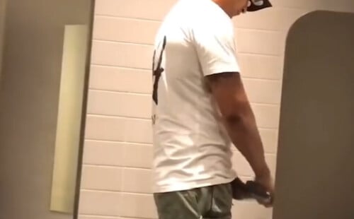 Latin dude peeing at urinal